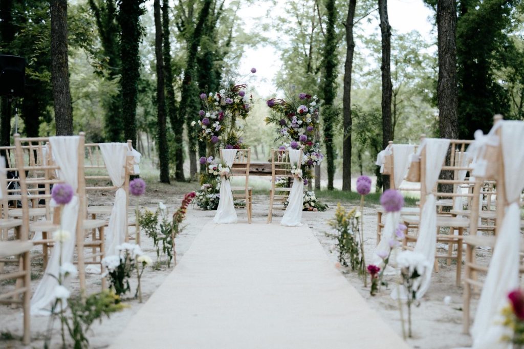 Cerimonia all'aperto con sedie chiavari e arco floreale viola