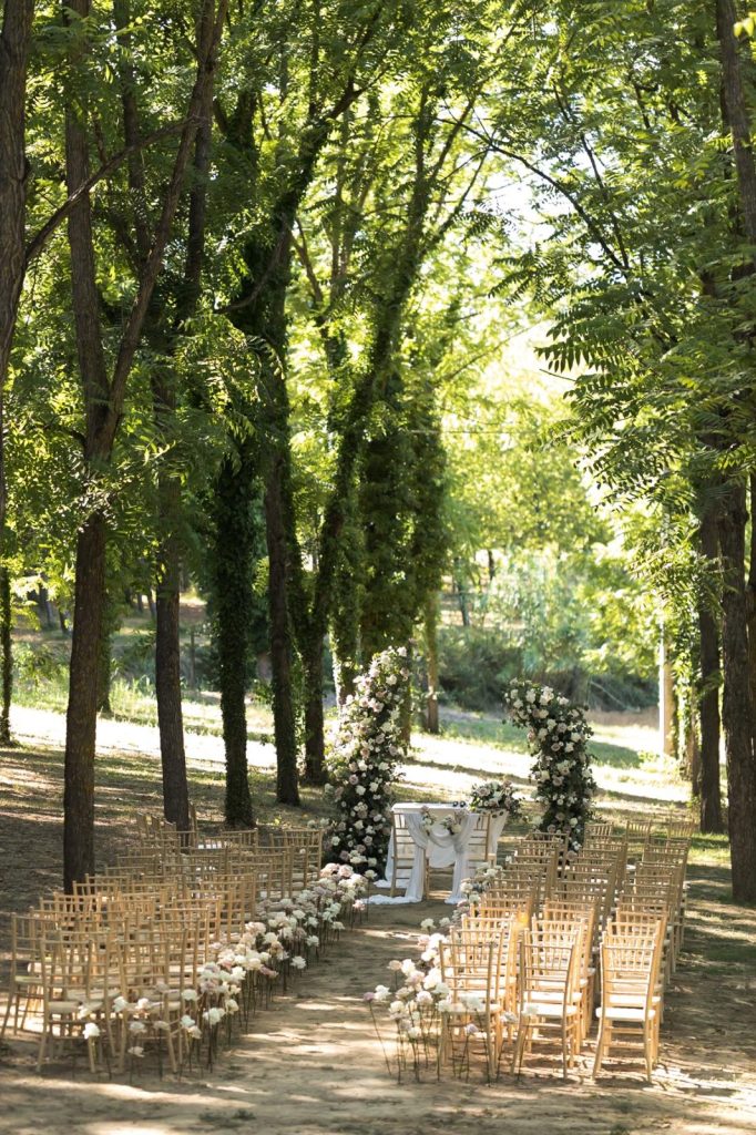 Cerimonia outdoor con sedie chiavari e arco floreale dai toni scuri