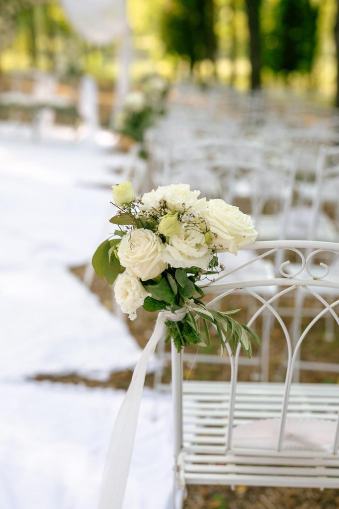 Dettaglio sedia in ferro bianco con bouquet di rose bianche in primo piano