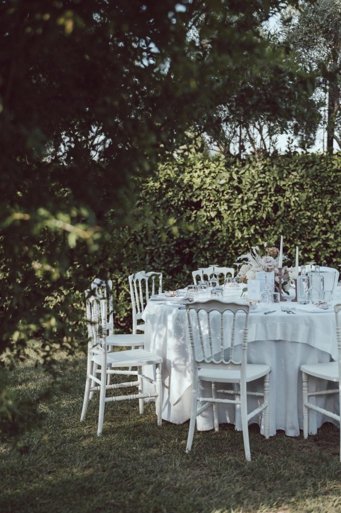 Tavolo rotondo in giardino con sedie chiavari bianche e tovaglia lunga